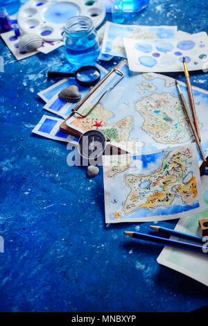 Handpainted fantasy map on a navy blue background with copy space. Artist workplace with watercolor sketches. Creative travel concept. Stock Photo