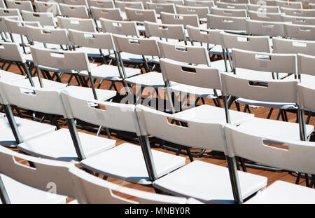 Rows of white empty folding chairs in a summer theatre. Stock Photo
