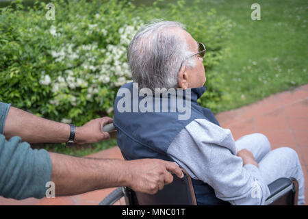 Helping elderly man on wheelchair Stock Photo