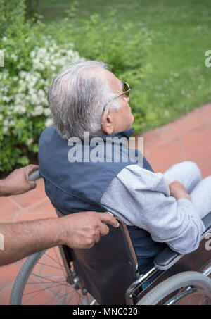 Helping elderly man on wheelchair Stock Photo