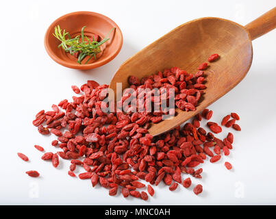 scoop of healthy goji berries and bowl of rosemary twigs on white background Stock Photo