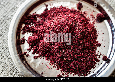 Dried Sumac, sumah or sumak on silver plate (arabic cuisine) Organic Concept. Stock Photo