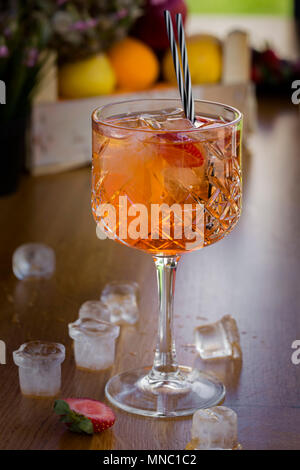 Cocktail with vodka, strawberries and lemon in glass on the bar with ice cubes Stock Photo