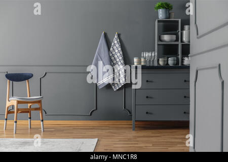 Wooden chair, cloths, and grey chest of drawers in a kitchen interior Stock Photo