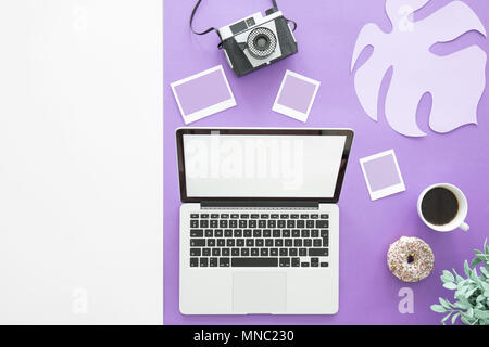 Copy space and laptop on an ultra violet background with photos, coffee and doughnut Stock Photo