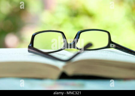 Closeup of Glasses Lying on an open Book Outdoors Stock Photo