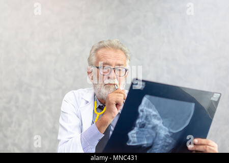 Senior medical doctor or chief doctor or Surgeon are checking skull of human head via x-ray film In examination room. Stock Photo