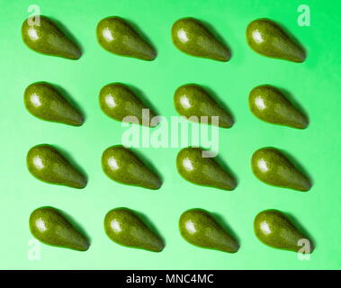 Avocado pattern slices on green background. Healthy food Stock Photo