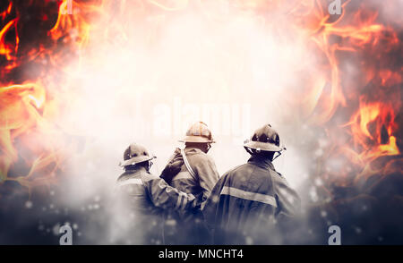 Group of firefighters fighting a fire, They are in the midst of fire and smoke. Stock Photo