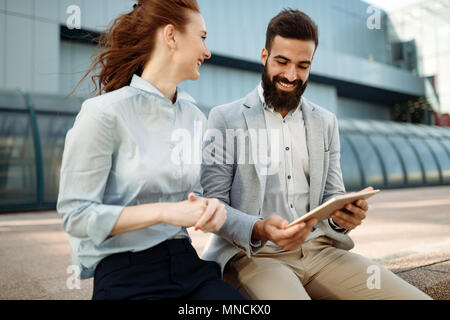 Two smiling young business people working on tablet outdoors Stock Photo