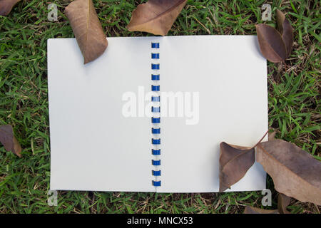 white notebook open on green grass background and texture Stock Photo