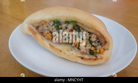 Vietnamese pork Banh Mi sandwich with carrot and spring onion on white dish , selective focus