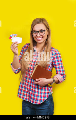 Young woman with book, card and flags of different speaking countries. Studio portrait of young beautiful female student Stock Photo