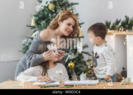 Boy looking at mother holding mask on sister's face at home Stock Photo