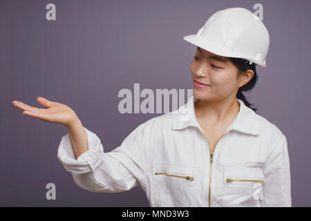 Confident young female construction worker gesturing against purple background Stock Photo