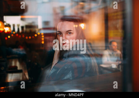 Beautiful young woman seen through cafe window Stock Photo