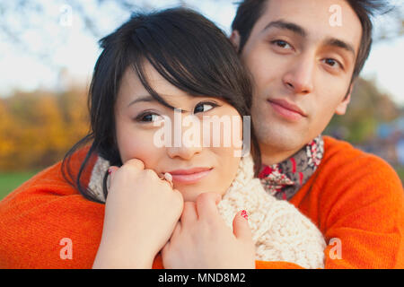 Thoughtful loving couple embracing in park during winter Stock Photo