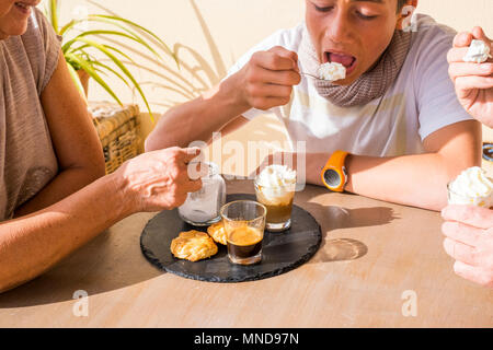 generational breakfast. coffee and cream with biscuits ad suger. old hands and young boy eating. summer time. Stock Photo