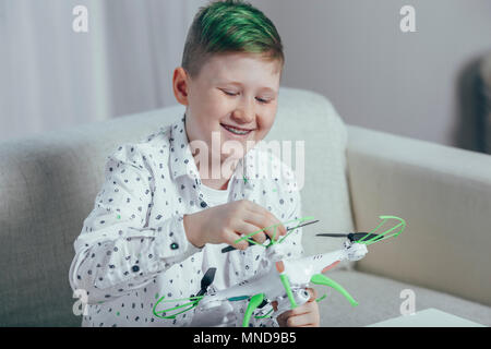 Smiling boy adjusting drone while sitting on sofa at home Stock Photo
