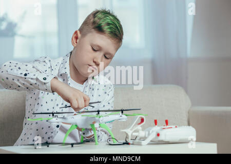 Confident boy adjusting drone on coffee table while sitting at home Stock Photo