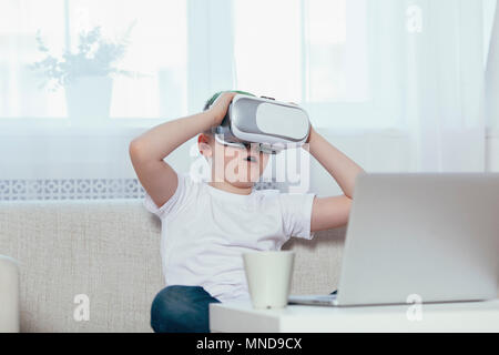 Boy wearing virtual reality headset while sitting on sofa at home Stock Photo