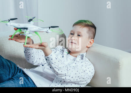 Smiling boy lying on sofa holding drone in living room at home Stock Photo
