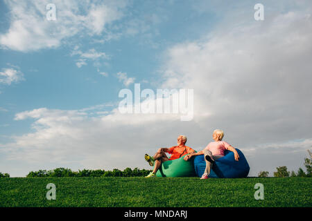 Senior couple sitting on beanbags on grass Stock Photo