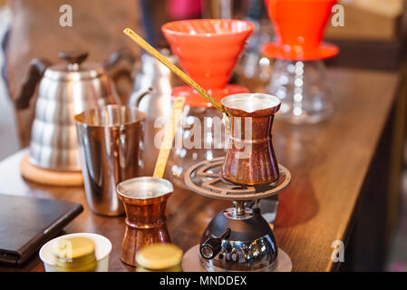 Portioned copper turks for cooking coffee on the mobile gas-jet and ceramic drip brewing, filtered coffee professional barista stuff on the wooden tab Stock Photo