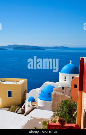 Stereotpyical view of Santorini, greece with white houses beside ocean, blue domed roofs Stock Photo