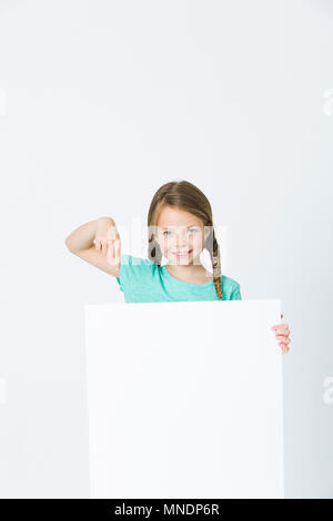 pretty, brunette girl is pointing at white board in front of white background Stock Photo