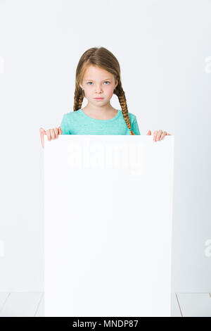 pretty, brunette girl is pointing at white board in front of white background Stock Photo