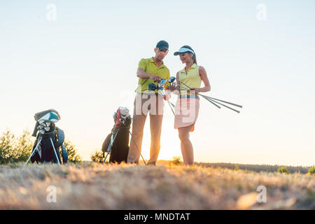 Golf instructor teaching a young woman how to use different golf clubs Stock Photo