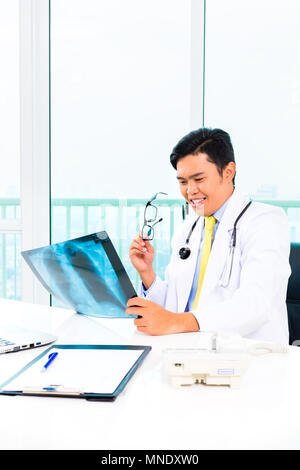 Asian doctor examining x-ray picture in practise Stock Photo