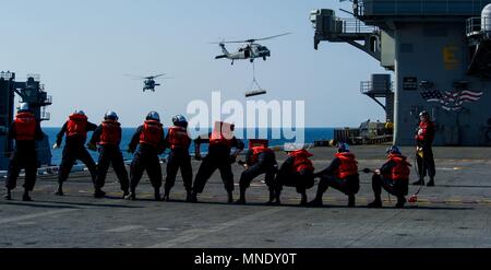 180515-N-OY799-0290 WATERS SOUTH OF JAPAN (May 15, 2018) Sailors from deck department man the phone-and-distance line on the flight deck as MH-60S Sea Hawks, assigned to Military Sealift Command (MSC) dry cargo/ammunition ship USNS Cesar Chavez (T-AKE 14), deliver ordnance to the Navy's forward-deployed aircraft carrier, USS Ronald Reagan (CVN 76), as part of a replenishment-at-sea during sea trials, May 15, 2018. The non-combatant, civilian-crewed ship, operated by MSC, provides fuel, food, ordnance, spare parts, mail and other supplies to Navy ships throughout the world. Ronald Reagan, the f Stock Photo