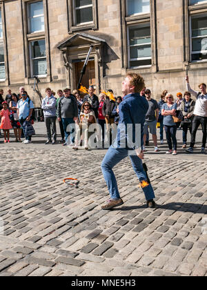 Royal Mile, Edinburgh, 16th May 2018. Tourists enjoying the sunshine and street entertainment on the Royal Mile, Edinburgh, Scotland, United Kingdom. Tourists watch a street performer called Daniel, whose act includes juggling flaming torches and large knives and machetes Stock Photo