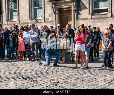 Royal Mile, Edinburgh, 16th May 2018. Tourists enjoying the sunshine and street entertainment on the Royal Mile, Edinburgh, Scotland, United Kingdom. Tourists watch a street performer called Daniel, whose act includes juggling flaming torches and large knives and machetes Stock Photo