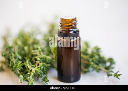 Thyme essential oil bottle with bunch of thyme herb. close up Stock Photo
