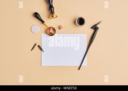 Flat lay of feminine desk workspace with copy space. Calligraphic style, paper on beige background. Top view of minimal composition with copy space. Stock Photo