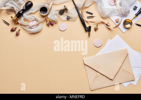 Flat lay of feminine desk workspace, home office with copy space. Calligraphic style, paper and envelope on beige background. Top view with copy space Stock Photo