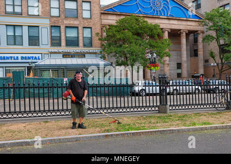 Boston, Massachusetts, USA - September 14, 2016: A landscape worker at Boston's Commons poses for picture holding a weed eater showing pride in his wo Stock Photo