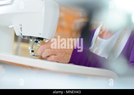 Closeup of female hands using sewing machine Stock Photo