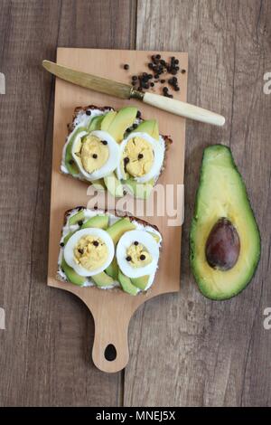 Slices of bread topped with avocado, egg and peppercorns Stock Photo