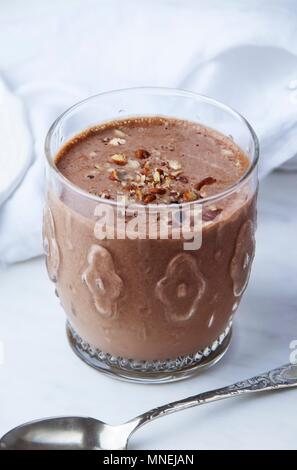 A high-protein chocolate & almond smoothie in a glass, topped with chopped nuts Stock Photo