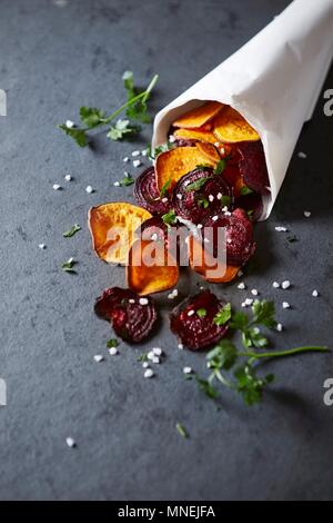 Homemade sweet potato and beetroot crisps in a paper bag Stock Photo