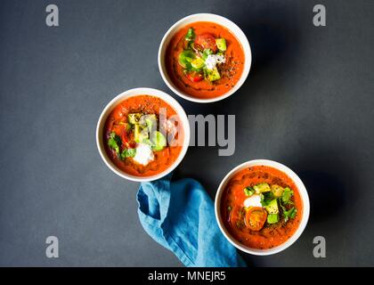 Chilled heirloom tomato gazpacho soup topped with avocado, cherry tomatoes, cilantro and a dallop of sour cream Stock Photo