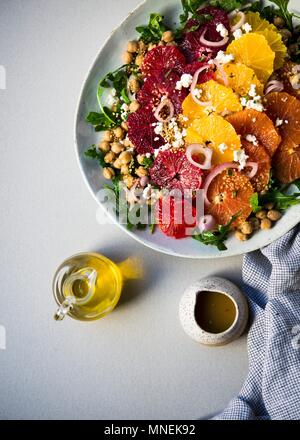 Three types of orange slices, blood, cara cara and navel oranges on top of a bed of chickpea arugula salad Stock Photo