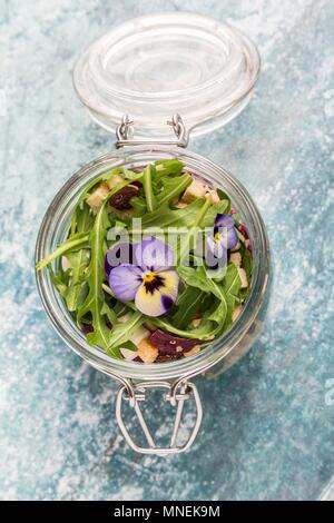 Quinoa salad with lambs lettuce, radicchio, rocket, croutons, goat's cheese and horned violets in a glass jar Stock Photo