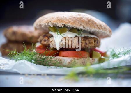 A burger with a millet fritter, tomato, and a dill and cucumber sauce (Vegan) Stock Photo