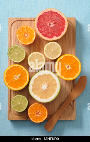 Halved citrus fruits on a wooden board Stock Photo