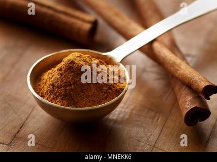 Ground Cinnamon in a Measuring Spoon; Cinnamon Sticks Stock Photo